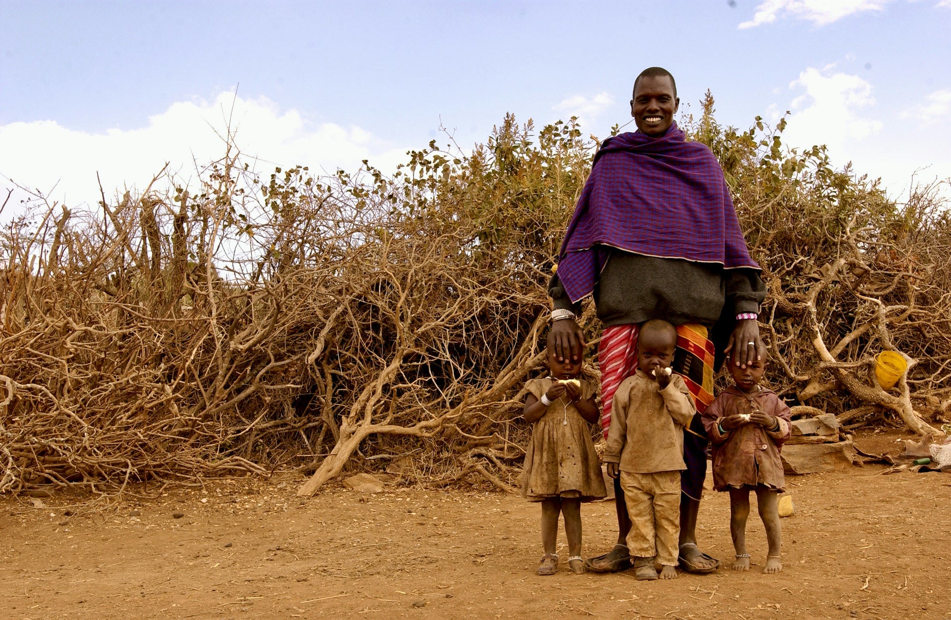A Maasai man and children standing in the Kenyan landscape